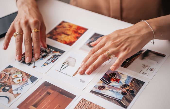 Hands arranging photo prints on a table, showcasing creativity and organization in content creation.