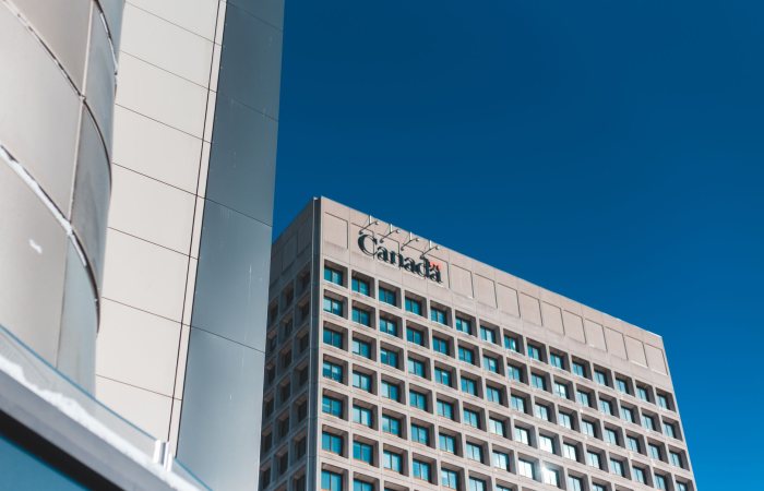 Low angle view of a modern skyscraper in Canada against a clear blue sky.