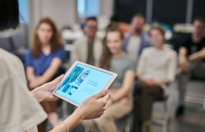 Business seminar with participants focused on a tablet presentation in an office setting.