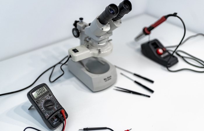 A laboratory workbench featuring a microscope, multimeter, and precision tools for scientific research.