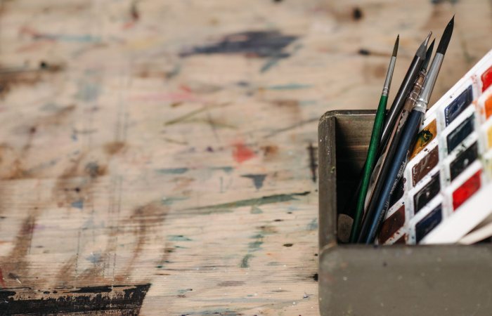 Close-up of watercolor paints and brushes in a workshop setting.