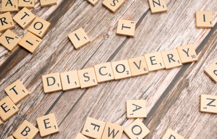 Close-up of wooden letter tiles on a table spelling 'Discovery', representing exploration and creativity.
