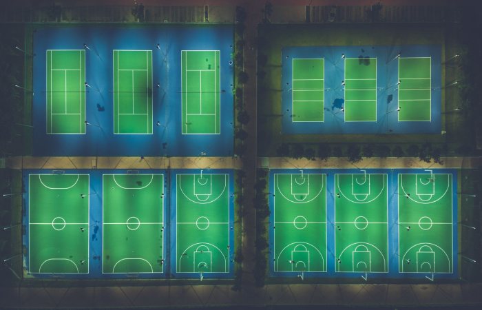 A captivating aerial view of illuminated sports courts at night showcasing patterns and symmetry.