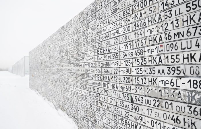 A wall of license plates in a snowy winter setting, creating a unique and textured art piece.